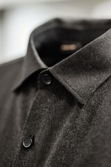 Close-up of a dark gray collared shirt's collar and top buttons, showcasing its texture and subtle speckling
