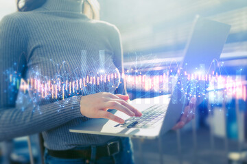 Businesswoman holding laptop with global financial graphs