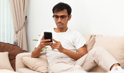 man using application on smartphone during sitting on sofa at home