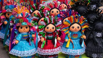 Fototapeta premium A group of dolls with colorful dresses and hair. They are arranged in a row. Historic center of Queretaro City, decorations and traditions to celebrate Mexico's Independence Day, colonial architecture