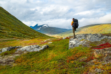Young woman with backpack in mountains. Sarek National Park, Sweden.