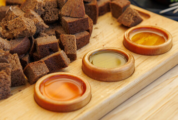 Three small bowls of different colored liquids on a wooden board