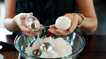 A woman holds up and displays a perfect, freshly made bath soap ball, showing the successful result of a hands-on creative workshop focused on making natural, homemade spa and beauty products