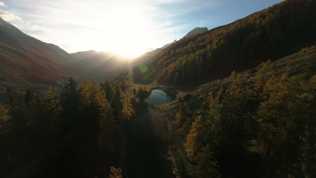 FPV flight over a lake on a mountain with yellow conifer trees, autumn, Switzerland
