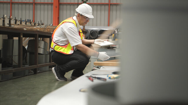 Industrial worker inspecting inside a large metal tube in a factory wearing safety helmet - Powered by Adobe