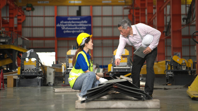 Senior engineers and young female workers are talking and inspecting steel plates - Powered by Adobe