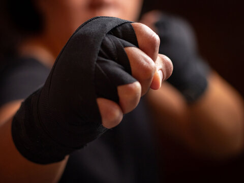 Close up female boxer with fists and black hand wraps.