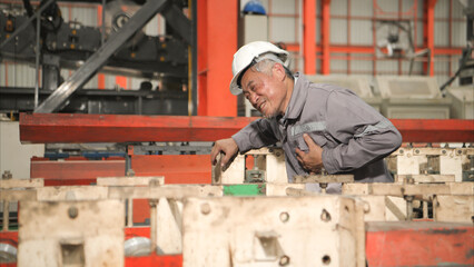 Industrial worker in protective gear experiencing chest pain while working