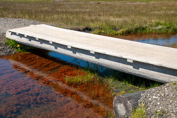 Stokksnes Iceland,  wooden bridge across clear stream in middle of wetland