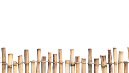 A rustic wooden fence made of bamboo sticks stands against a plain white background. creating a serene and minimalist aesthetic ideal for nature-themed projects or home decor