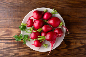 Fresh small red radishes on wooden background