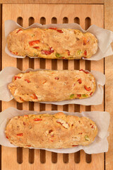 Three freshly baked bread loaves with chunks of red Macedonian sweet pepper, arranged on a wooden board