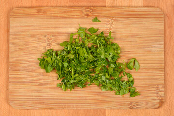 A pile of freshly chopped parsley is on a wooden cutting board