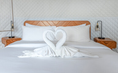 Single bed with heart shaped white towels on the bed