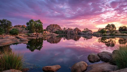 Tableau sur plexiglas Réflexion Peaceful sunrise over a tranquil lake, reflected in still water.  Rocky shores, trees, and a vibrant sky  © Azkila