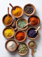 An overhead shot of ten small wooden bowls filled with various colorful spices and herbs, arranged on a white surface.  Wooden spoons and a nutmeg are also present