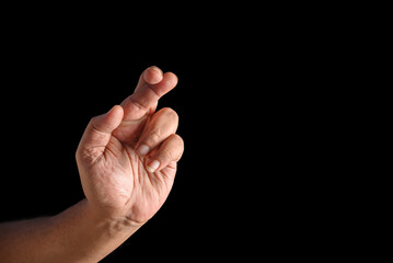 Hand Crossing Fingers Gesture on a Black Background Displaying Hope and Luck