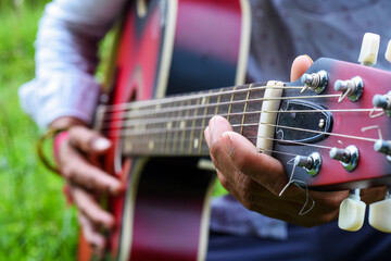 Close-Up of Hands Playing a Guitar Outdoors on a Sunny Day