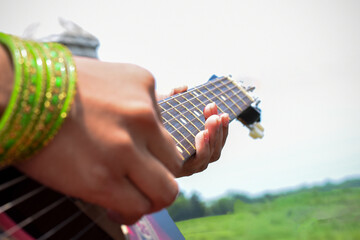 Close-Up of Hands Playing a Guitar Outdoors on a Sunny Day