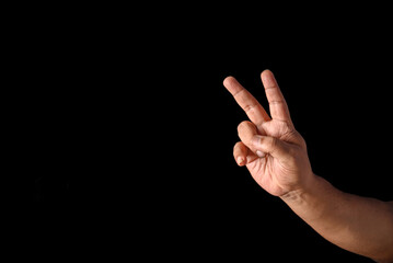 Hand Displaying Peace Gesture Against Black Background