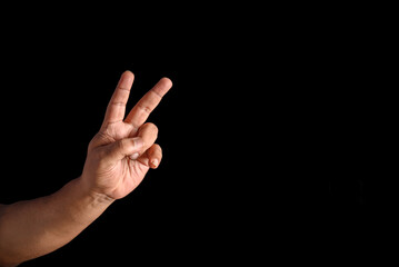 Hand Displaying Peace Gesture Against Black Background