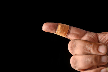 Injured Finger Covered With Band-Aid on a Dark Background