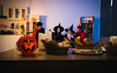 A cheerful group of friends dressed as witches and devils celebrate Halloween together,raising glasses of wine around a festive table with pumpkins,candles, bread,decorations in  cozy indoor setting