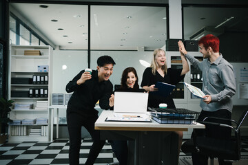 Four colleagues engage in a collaborative office meeting, using laptops, tablets, and documents to brainstorm ideas, discuss strategies,share insights, fostering teamwork, productivity, professional