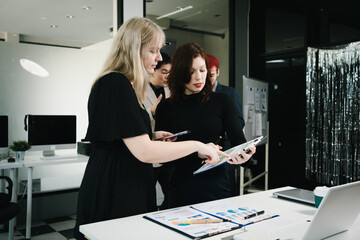 Four colleagues engage in a collaborative office meeting, using laptops, tablets, and documents to brainstorm ideas, discuss strategies,share insights, fostering teamwork, productivity, professional