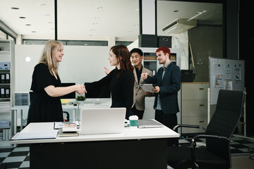 Four colleagues engage in a collaborative office meeting, using laptops, tablets, and documents to brainstorm ideas, discuss strategies,share insights, fostering teamwork, productivity, professional