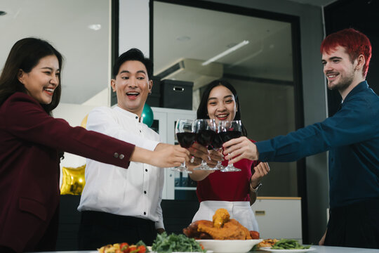 Four cheerful friends celebrate together in an office party, enjoying delicious food, fried chicken, pizza, salad, wine. Surrounded by balloons and laughter, they share happiness, marking   year-end