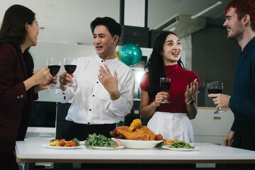 Four cheerful friends celebrate together in an office party, enjoying delicious food, fried chicken, pizza, salad, wine. Surrounded by balloons and laughter, they share happiness, marking   year-end