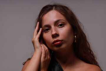 Fototapeta premium Close studio portrait of pretty young brunette woman on gray background