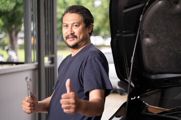 An Asian man and his tools are maintaining his car by himself.
