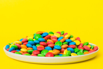 Multicolored candies in a bowl on a colored background. birthday and holiday concept. Top view with copy space