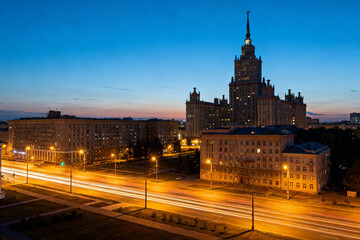 Fototapeta premium Cityscape at twilight with illuminated streets and a prominent high-rise building