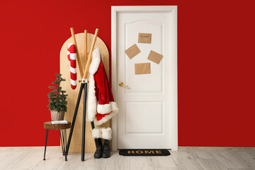 Obraz premium Interior of hallway with decorated door, Santa costume and Christmas tree near color wall