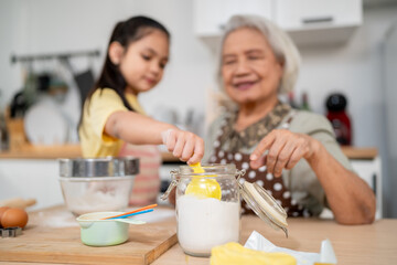 Asian granddaughter baking bakery with grandmother in kitchen at home. 