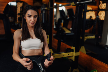 Determined sportswoman doing seated cable rows exercise in modern gym