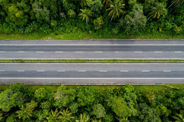 Aerial view of a straight highway cutting through dense tropical forest
