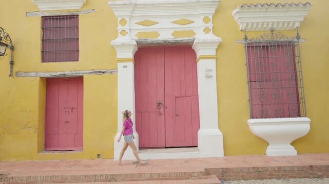 Female tourist walking along a colorful street with colonial architecture in mompox, colombia