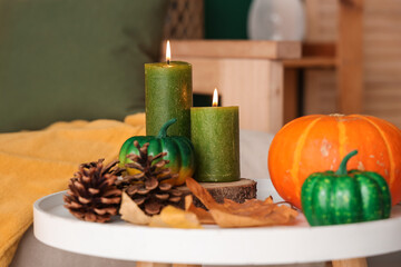 Pumpkins, candles, cones and autumn leaves on coffee table in living room. Closeup