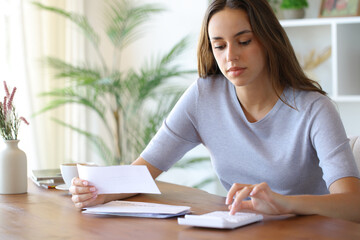 Woman using calculator holding bill in a room