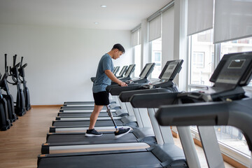 Asian young man with prosthetic leg walk on a treadmill at the gym.