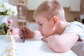 A boy with hearing aids engages with a smartphone, playing mobile games with focused enjoyment....