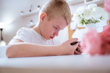 A boy with hearing aids engages with a smartphone, playing mobile games with focused enjoyment....