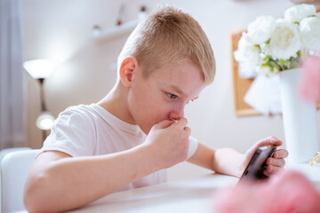 A boy with hearing aids engages with a smartphone, playing mobile games with focused enjoyment....