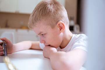 A boy with hearing aids engages with a smartphone, playing mobile games with focused enjoyment....