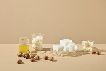 A warm beige scene with shea butter blocks, oil in glass, and shea nuts on a clean tabletop. Perfect for cosmetic ingredient product mockups.