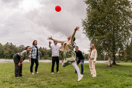 Group of people playing with a ball on a meadow in the park.